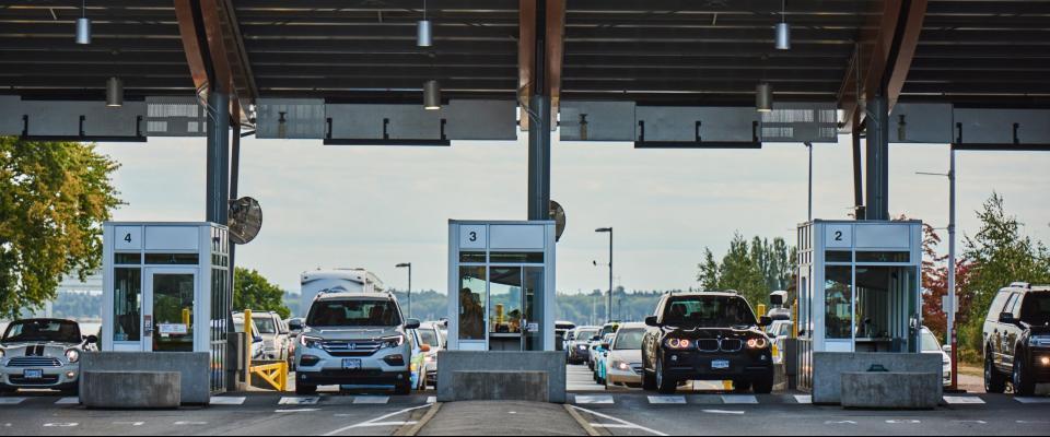 Plusieurs voitures sont arrêtées à un poste frontière entre les États-Unis et le Canada.