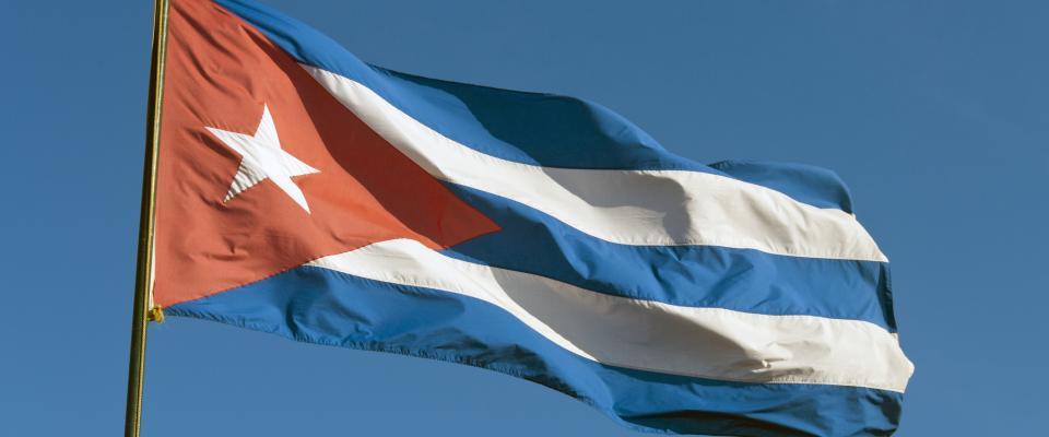 Un drapeau à rayures rouges, blanches et bleues flotte dans un ciel bleu limpide.