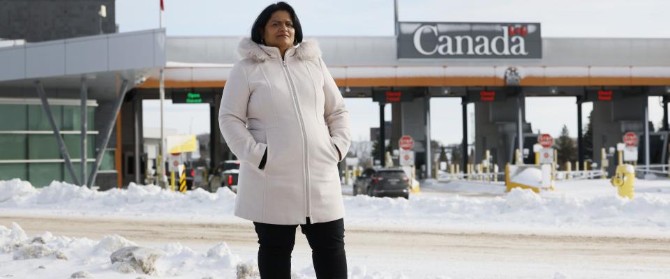 Sharon est dehors, devant un passage frontalier