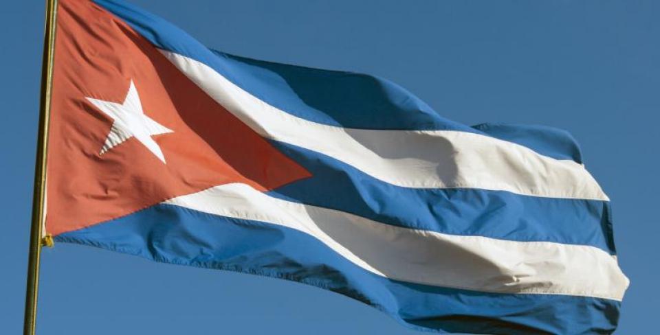 Un drapeau à rayures rouges, blanches et bleues flotte dans un ciel bleu limpide.